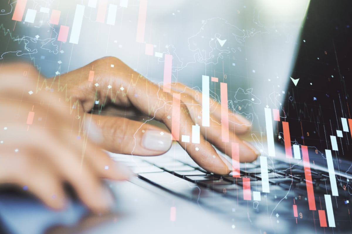 Hand using a computer with overlay of financial charts, illustrating data analysis and digital financial markets