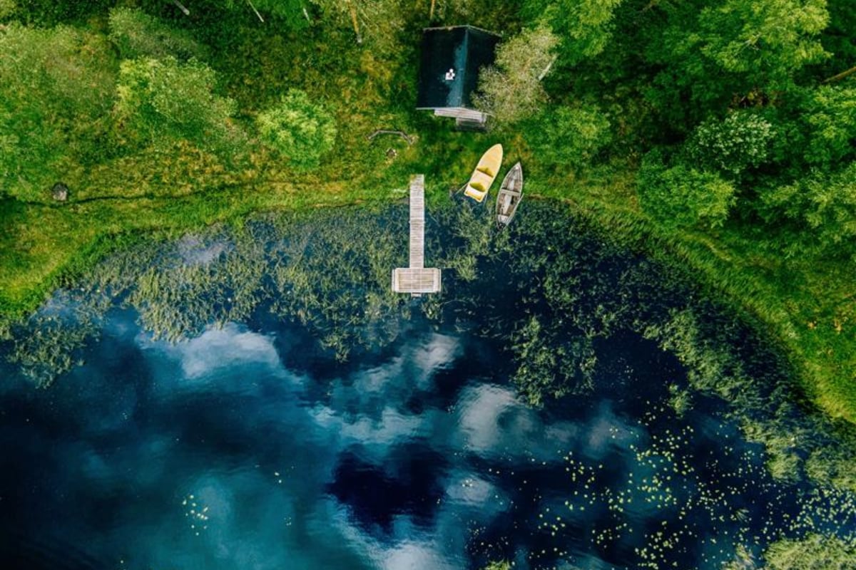 Aerial view of a small lake surrounded by vegetation with a wooden pier and boats, illustrating nature, biodiversity and sustainable landscapes
