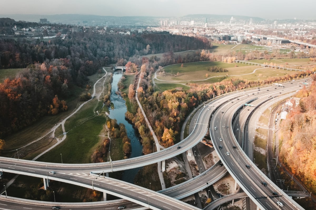 Aerial view of a highway interchange near a river with autumn trees, illustrating infrastructure, mobility and environment
