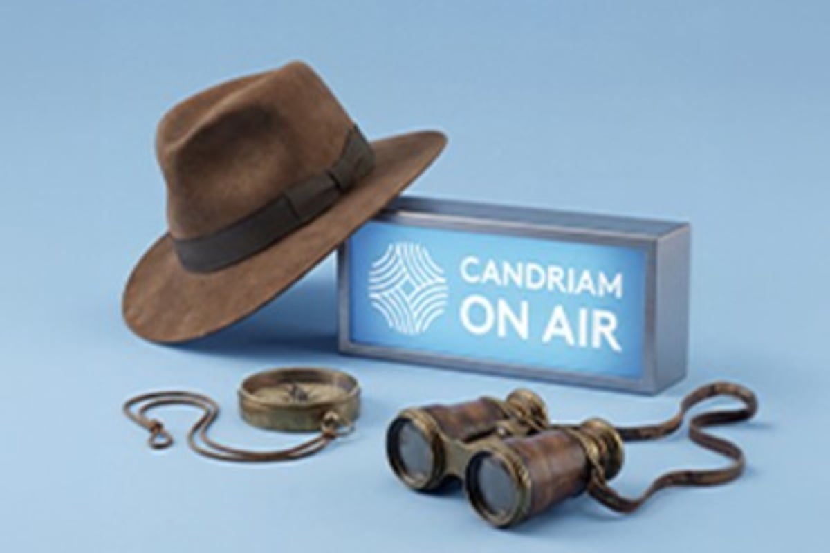 Exploration items including a hat, compass and binoculars next to a “Candriam On Air” sign, illustrating discovery, exploration and communication
