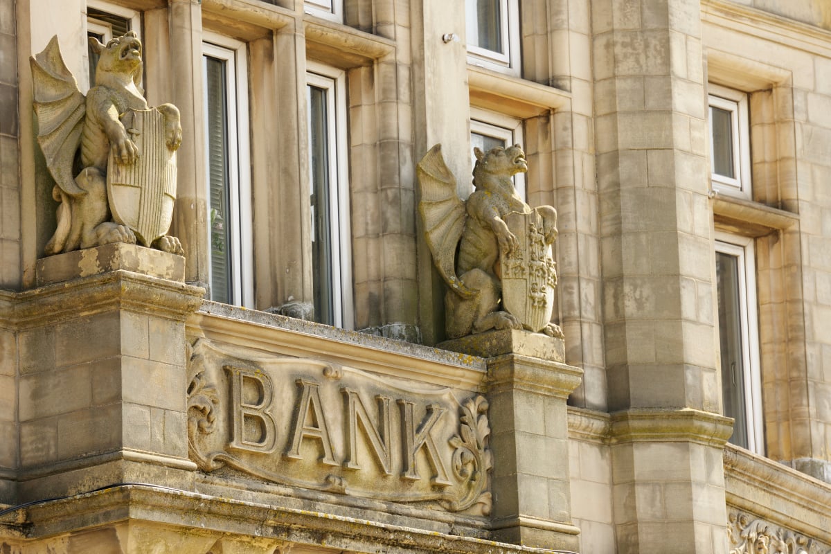 Stone facade of an old building with “BANK” inscription, illustrating the banking sector and financial institutions
