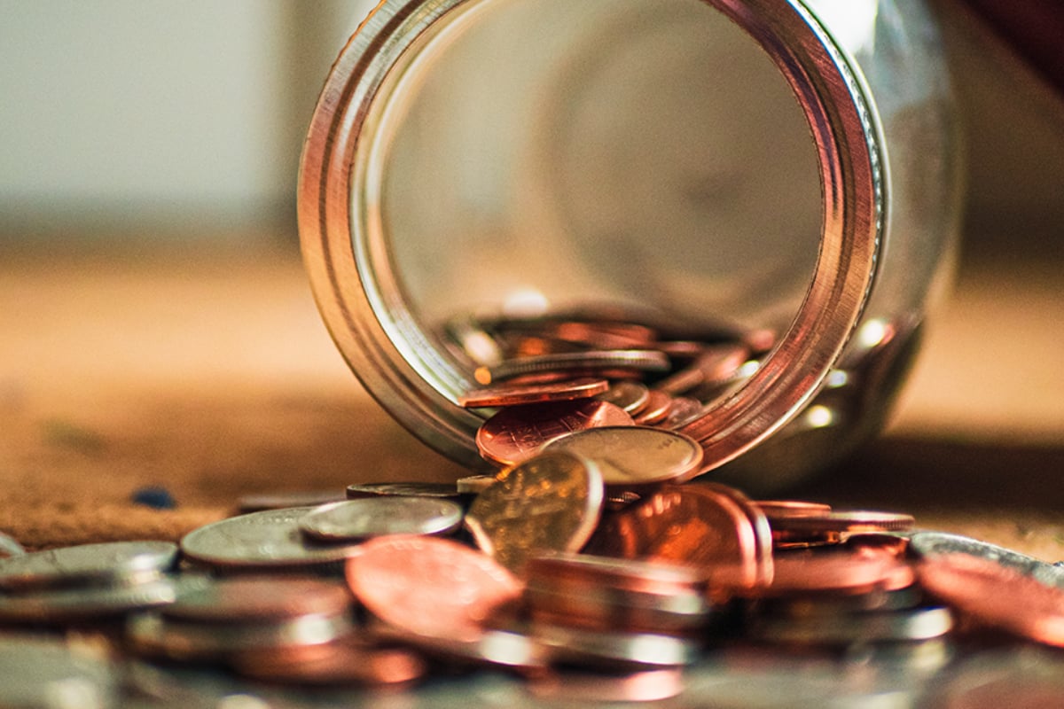 Coins spilling out of a glass jar, illustrating savings, personal finance and wealth management
