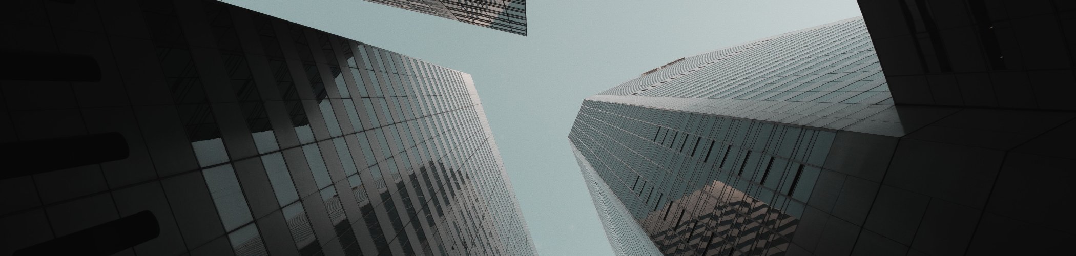 Modern glass skyscrapers viewed from below, illustrating economic growth and financial markets