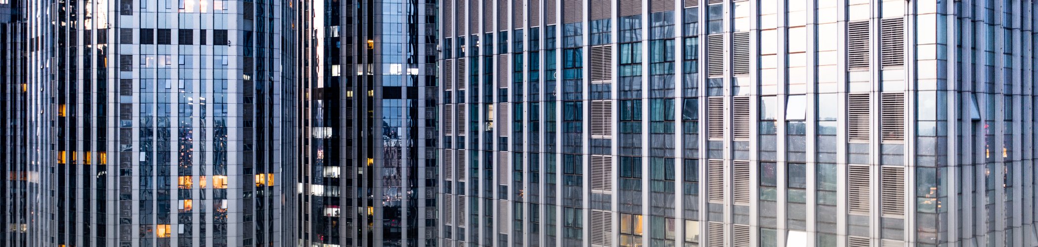 Modern glass and steel skyscraper facades in a financial district, illustrating corporate business and urban development