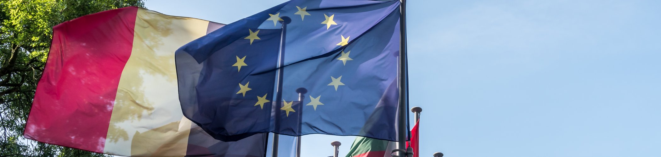 Belgian and European Union flags waving side by side, symbolizing European cooperation and unity