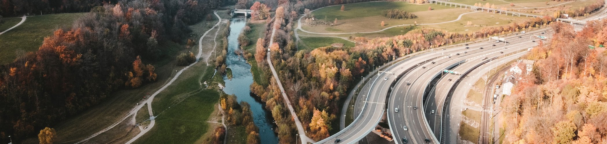 Aerial view of a highway interchange near a river with autumn trees, illustrating infrastructure, mobility and environment
