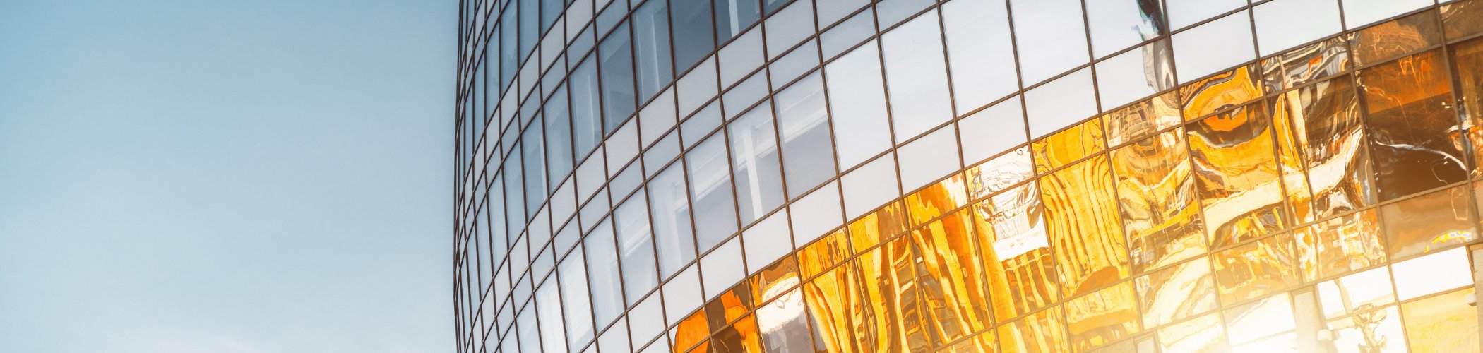 Glass skyscraper facade with golden reflections, illustrating modern real estate and financial markets
