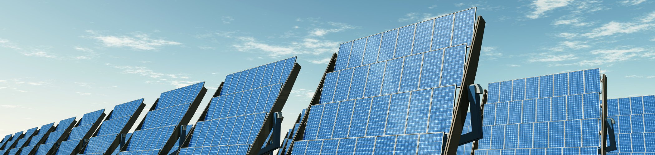 Rows of solar panels stand in a sunlit landscape beneath a blue sky with scattered white clouds.