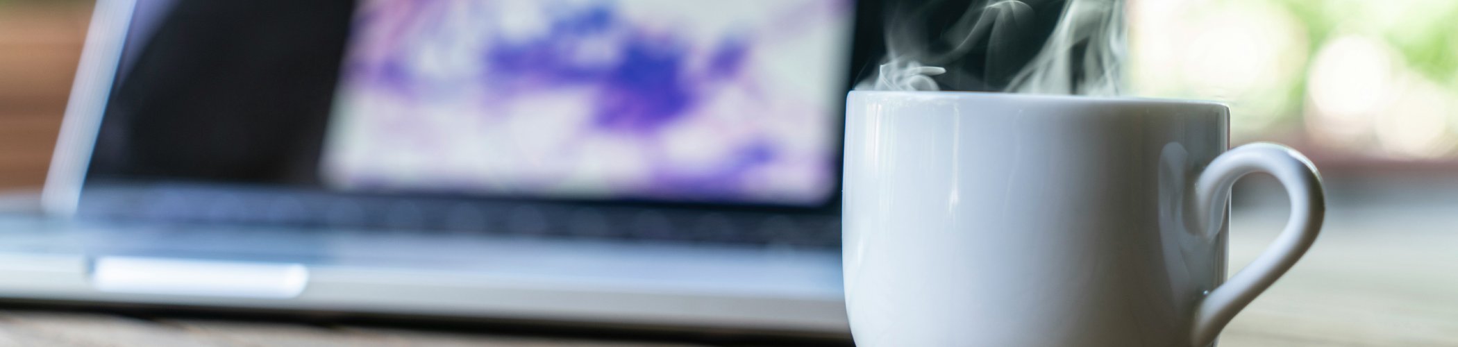 Coffee cup beside a laptop during a market analysis session, symbolizing investment insights and financial research