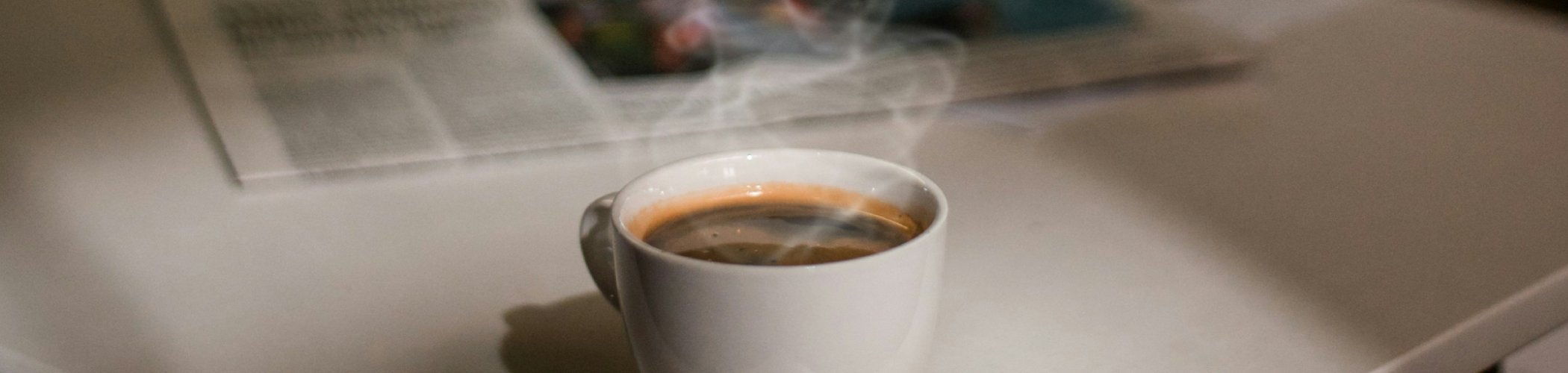 Cup of coffee beside a financial newspaper, symbolizing market analysis, investment insights and economic commentary