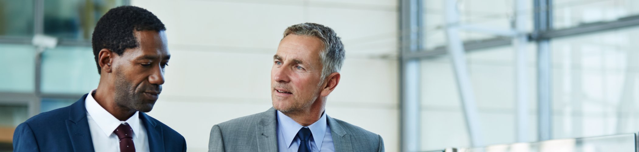 Two business professionals walking and talking in a modern building, illustrating collaboration, management and corporate strategy
