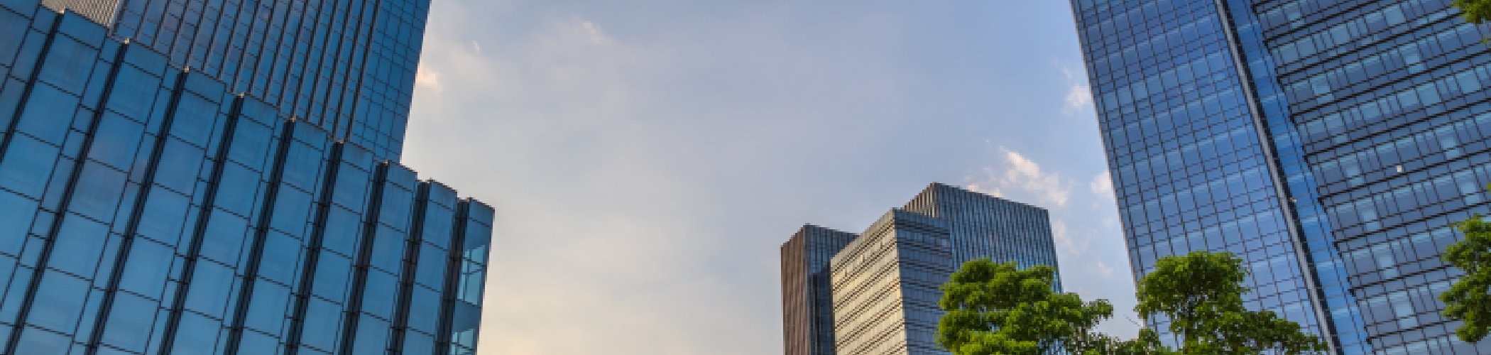 Modern sustainable office buildings with glass facades and green trees in an urban business district, representing responsible investment, ESG integration, and sustainable development.