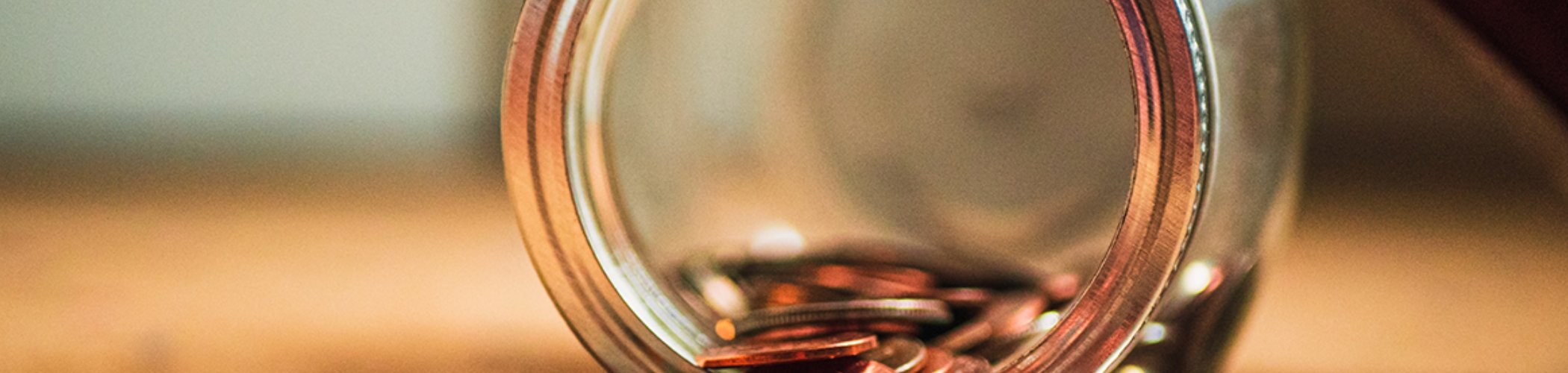 Coins spilling out of a glass jar, illustrating savings, personal finance and wealth management

