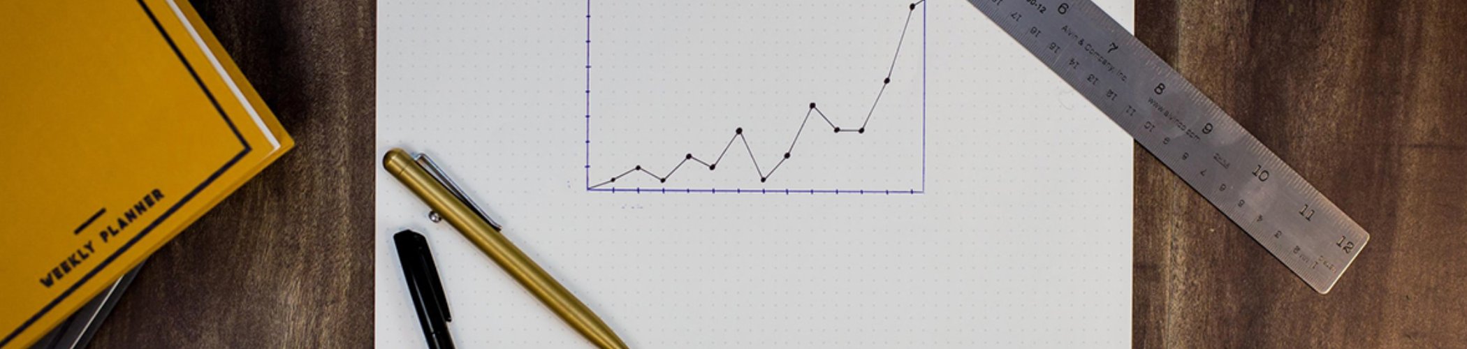 Upward performance chart drawn on grid paper with a metal ruler, illustrating data measurement and analysis
