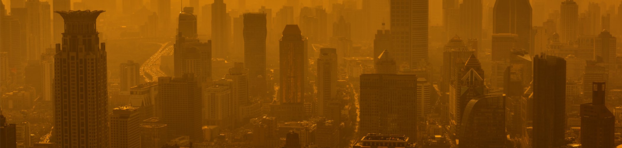 Urban skyline covered in dense orange haze, illustrating air pollution and inflationary pressures in an urban environment
