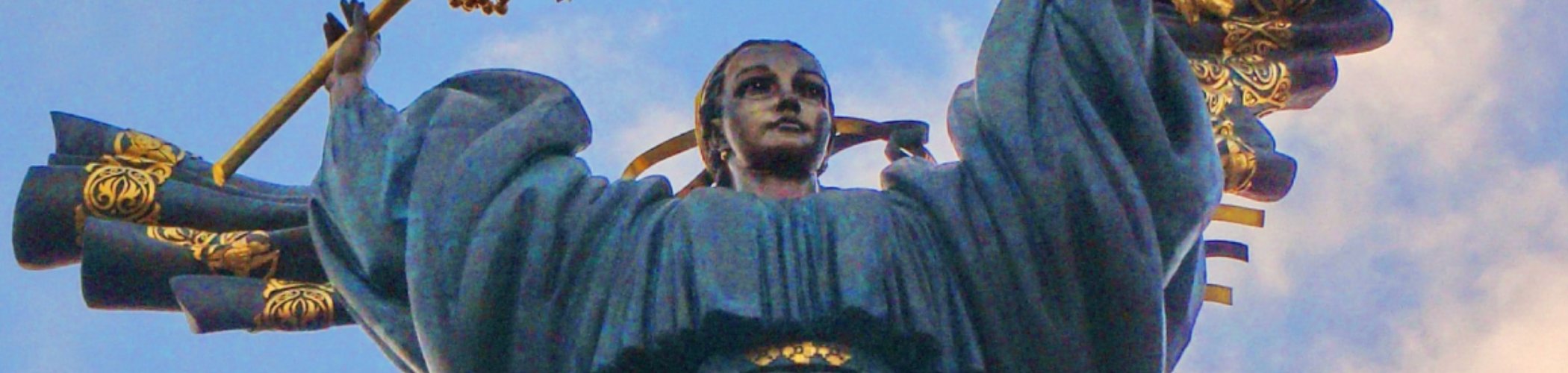Monumental statue with golden ornaments and raised arms holding symbols, illustrating Ukrainian culture, history and heritage
