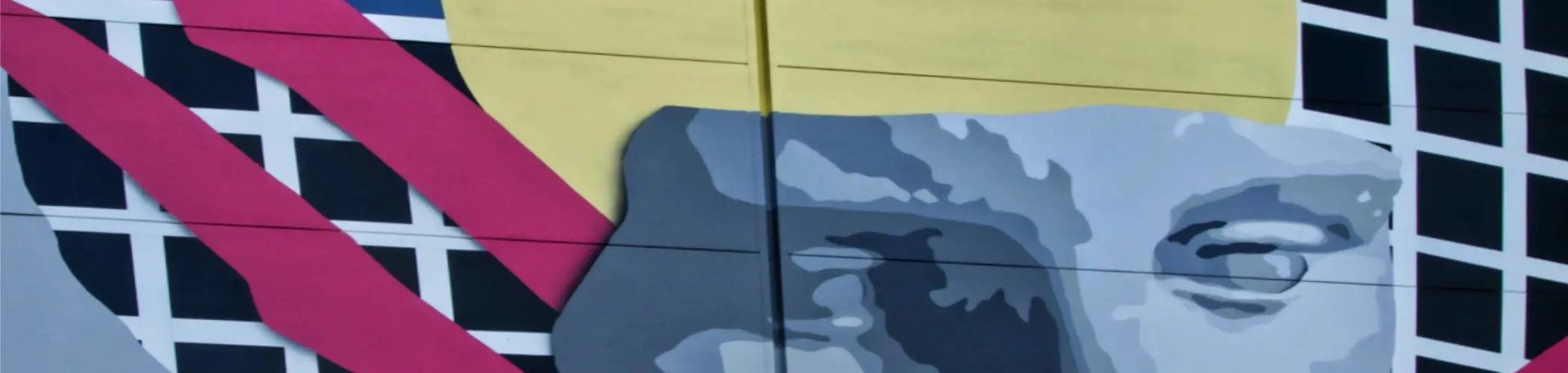 Large abstract mural depicting a stylized human face combined with geometric shapes and bold colors on a building façade.