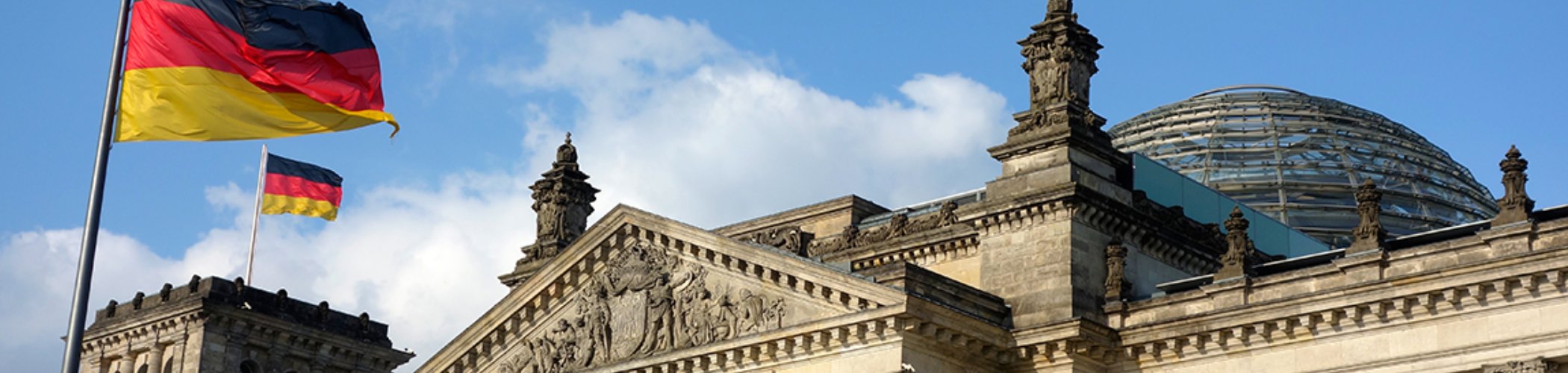 Bâtiment du Reichstag à Berlin avec drapeaux allemands flottant devant, illustrant la politique et les institutions en Allemagne
